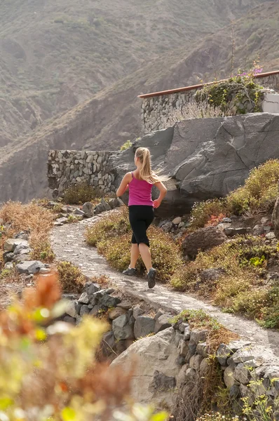 In forma. Giovane donna che corre su una strada di montagna — Foto Stock