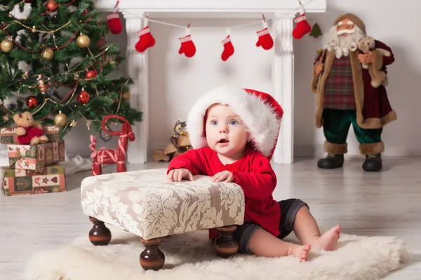 Un bambino sta fissando la telecamera indossando un cappello di Babbo Natale . Fotografia Stock