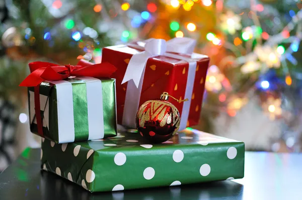 Festive gift boxes against glowing christmas tree — Zdjęcie stockowe