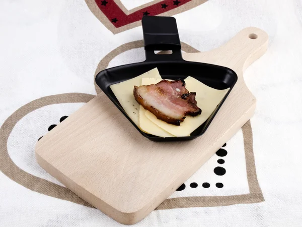 Raclette pan with cheese and bacon - party food — Stock Photo, Image