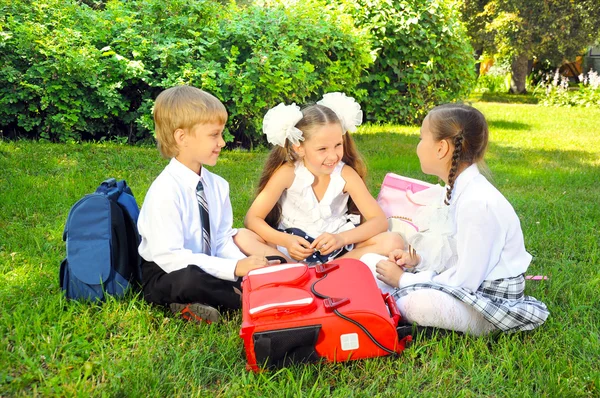 Schoolboy and schoolgirls in the park — Stock Photo, Image