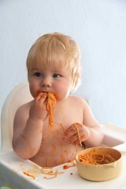 Küçük oğlan spagetti bolonez yiyor. Ortalığı dağıtan sevimli çocuk. Portreyi kapat