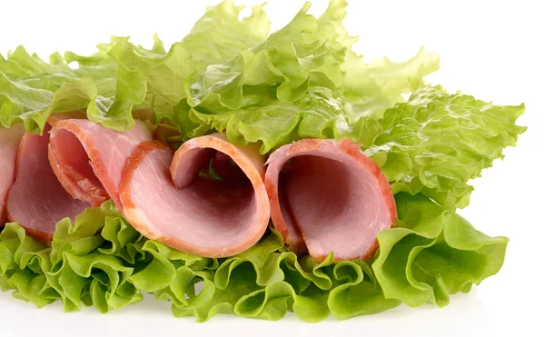 Fette di prosciutto su insalata verde, isolate su fondo bianco — Foto Stock
