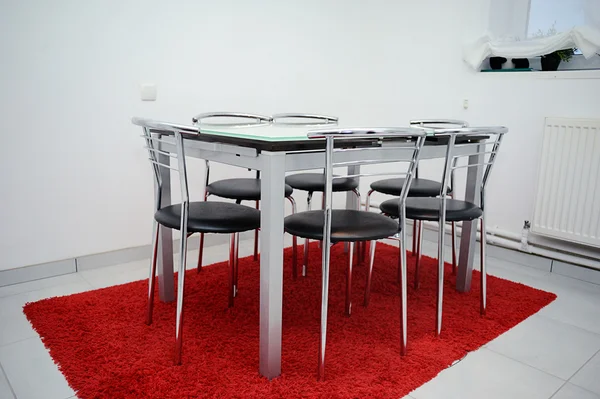 Interior of white kitchen with a table on red rug — Stock Photo, Image