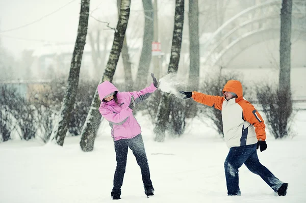 Pelea de bolas de nieve. Pareja de invierno divirtiéndose jugando en nieve al aire libre — Foto de Stock