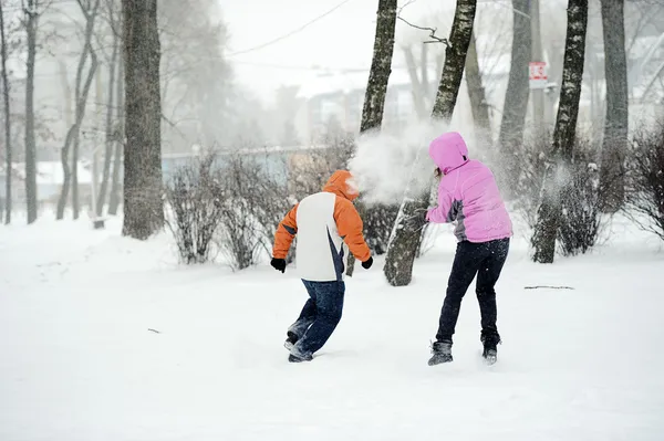 雪玉の戦い。冬のカップルが楽しんで屋外雪で遊んで — ストック写真
