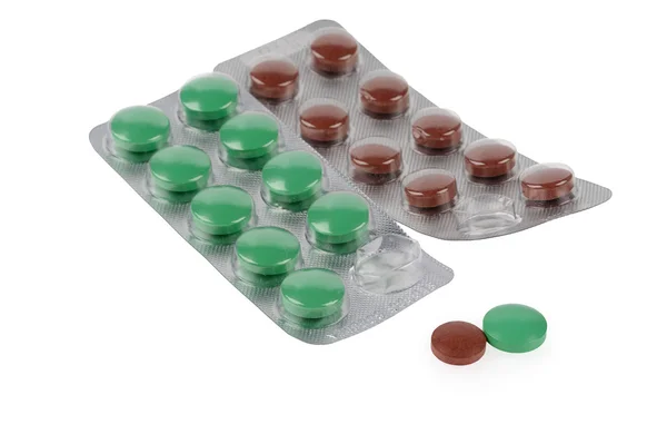 Зеленые и коричневые таблетки в волдырях на белом фоне — стоковое фото