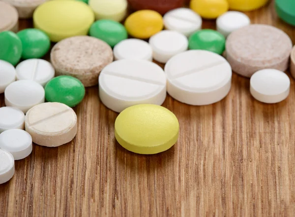 Pila di diverse pillole isolate su sfondo di legno — Foto Stock