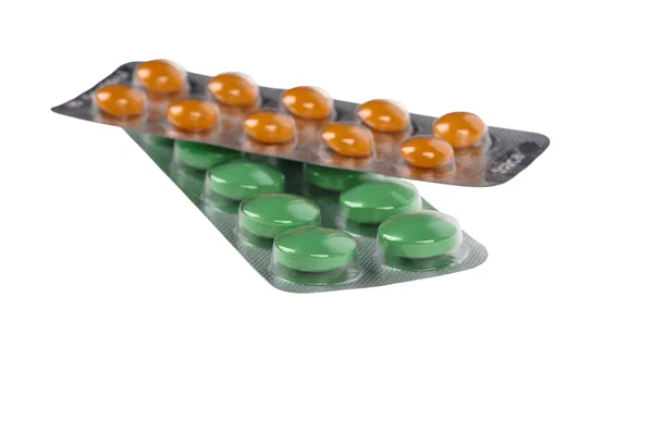 Зеленые и оранжевые таблетки в волдырях на белом фоне — стоковое фото