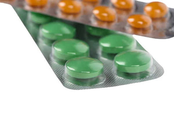 Green and orange pills in blisters on white background — Stock Photo, Image