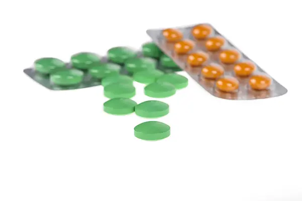 Green and orange pills in blisters on white background — Stock Photo, Image