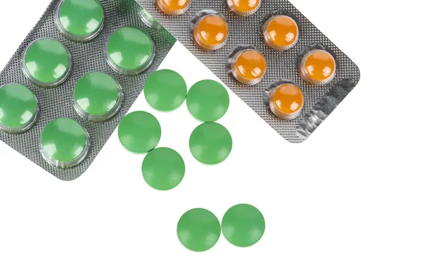 Gröna och orange piller i blåsor på vit bakgrund — Stockfoto