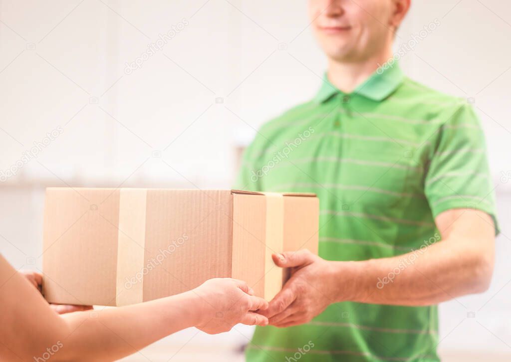 Woman hand accepting a delivery boxes from professional caucasian deliveryman at home.