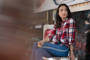 Genç ve güzel bir kadın stüdyoda ekose bir gömlekle poz veriyor.