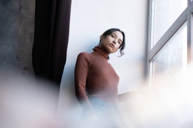 Stüdyodaki genç ve güzel bir kadının portresi, kot pantolonun içinde duruyor.