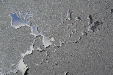 Siyah ıslak bir yolda su damlacıklarının dokusu, kenarlara sıçramış.