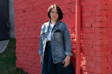 Genç ve güzel bir kadın dışarıda kot ceketle poz veriyor.