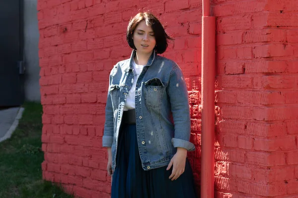 Genç ve güzel bir kadın dışarıda kot ceketle poz veriyor.