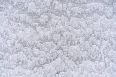 Kışın dışarıda, duvarda beyaz kar dokusu dalgalar halinde uzanıyor.