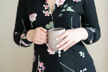 Stüdyoda kupa tutan genç ve güzel bir kadın.