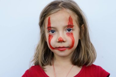 Küçük bir kızın portresi, yüzü kırmızı boyayla boyanmış.