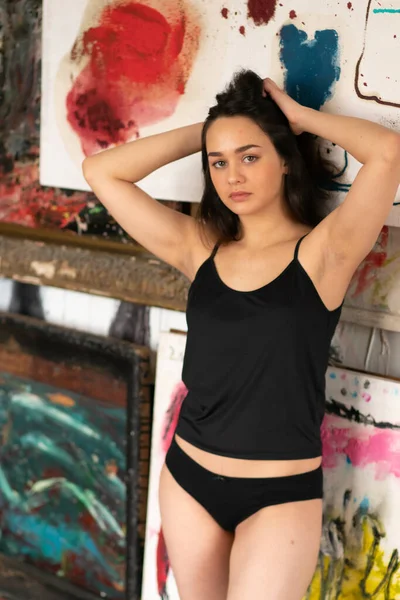 Genç ve güzel bir kadın stüdyoda siyah iç çamaşırlarıyla poz veriyor.