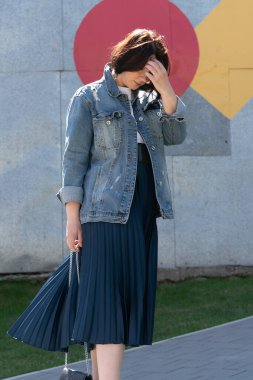 Genç ve güzel bir kadın dışarıda kot ceketle poz veriyor.