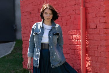 Genç ve güzel bir kadın dışarıda kot ceketle poz veriyor.