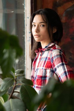 Stüdyoda kırmızı ekose gömlekli güzel bir kadın.