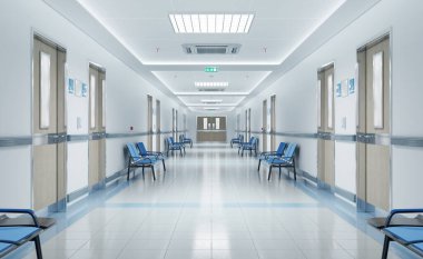 Odaları ve mavi koltukları olan uzun beyaz hastane koridoru. Boş bir kaza ve içinde parlak ışıklar olan acil bir iç mekan.