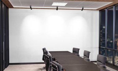 Blank white wall Mockup in dark modern office with windows and bright spotlights. Empty company meeting room 3D rendering
