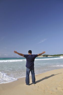 kumlu bir plaj üzerinde duran bir adam, Karayip Denizi, turkuaz mavi sularına doğru seyir kollarını neşe içinde yayıldı. sunular için kopya alanı bol.