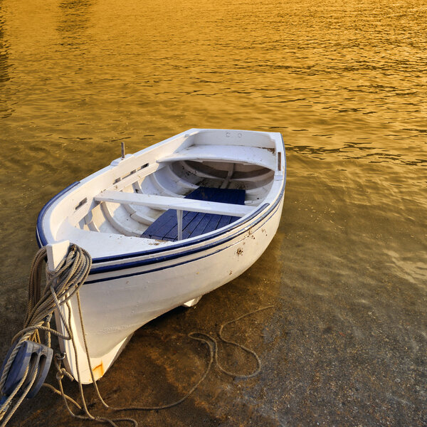 A small row boat beached on the shore at sunset - Cadaques, Spain