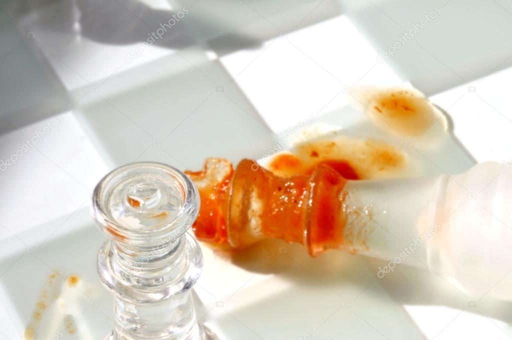 A bloody victory on a chess board - shallow depth of field shot of the black queen standing over the fallen white king, laying in a pool of blood