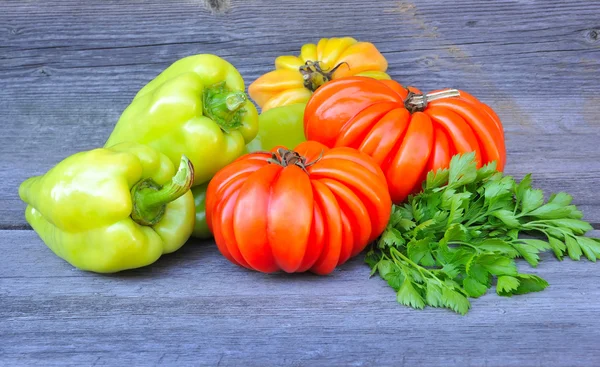 Verse tomaten (soort schoonheid lottringa), zoete groene paprika's en peterselie op een oude houten tafel — Stockfoto