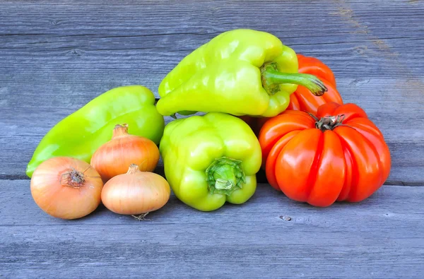 Verse zoete groene paprika's met ui en tomaten (soort schoonheid Lottringa) op een oude houten tafel — Stockfoto