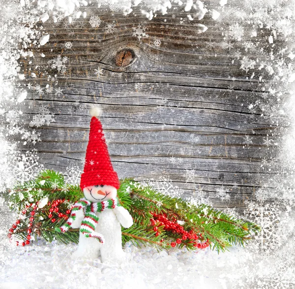 Sneeuwpop met de takken van Spar op een snowbound houten achtergrond — Stockfoto