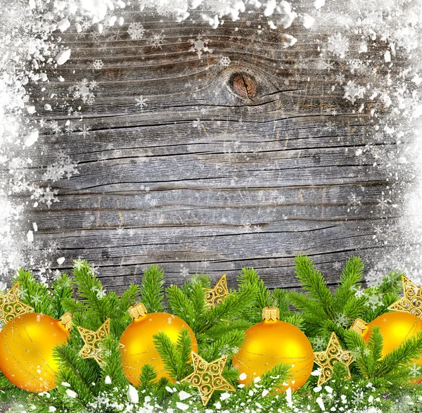Guld dekoration julgranskulor och furu på insnöade trä bakgrund — Stockfoto
