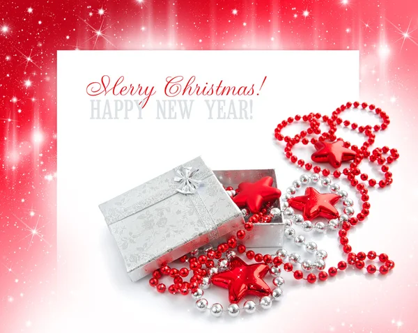 Een klein geschenk is met christmas kralen en door sterren op een feestelijke achtergrond — Stockfoto