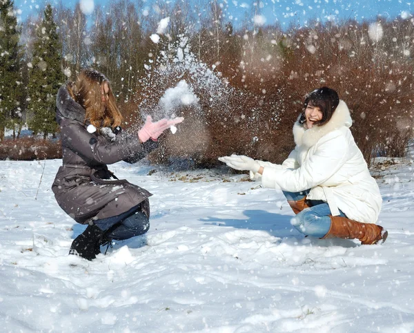 Dos chicas en invierno se lanzan a la nieve — Foto de Stock