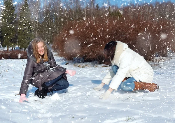 Dos chicas en invierno se lanzan a la nieve —  Fotos de Stock