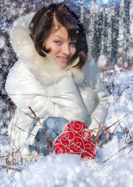 Winter girl with a decorative heart in snow — Stock Photo, Image