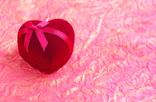 Caja de regalo en forma de corazón de terciopelo rojo sobre un fondo un papel de envoltura —  Fotos de Stock