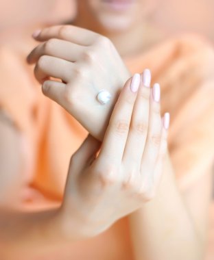 Young woman applies cream on her hands after bath. Focus on hand clipart