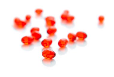 Vitamin yansımaları ile beyaz zemin üzerine kırmızı kapsül