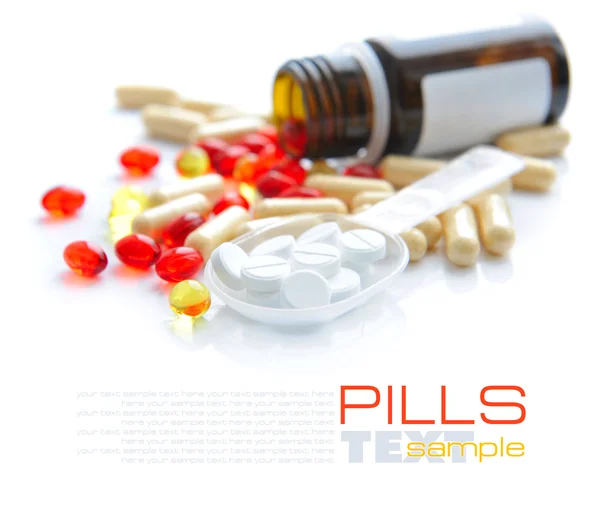 Tabletki są w łyżką na tle kolor kapsułki — Zdjęcie stockowe
