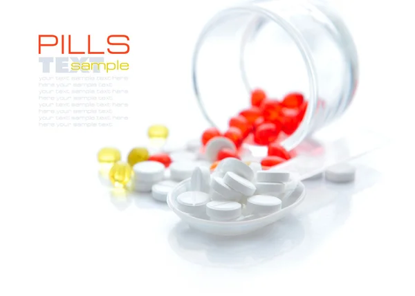 Tabletki są w łyżką na tle kolor kapsułki — Zdjęcie stockowe