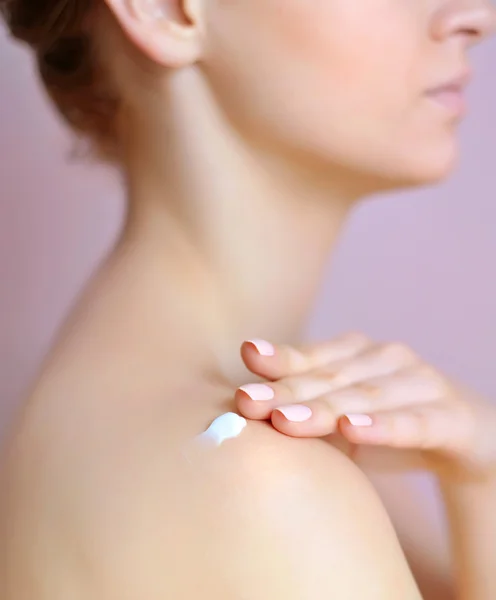 Schöne junge Frau mit Sahne auf der Schulter. Fokus liegt auf einer Hand — Stockfoto