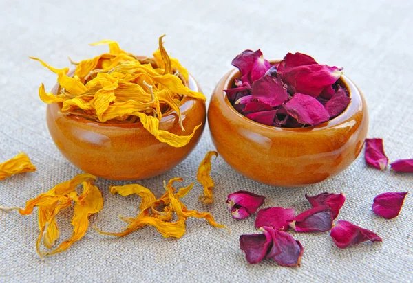 Сухие целебные цветы и лепестки в чашках на мешковине, травяная медицина — стоковое фото