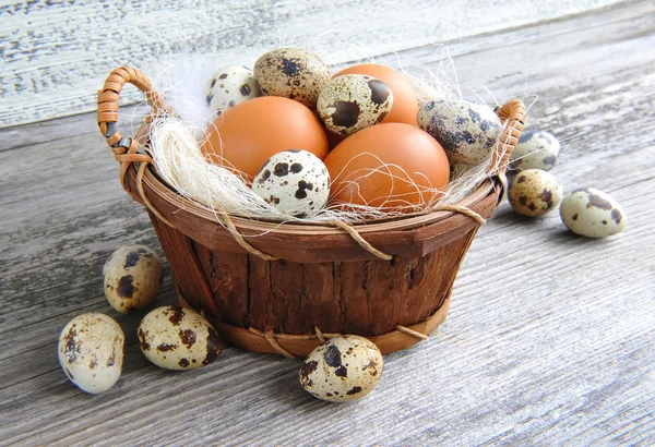 Verschillende soorten eieren in een mand op een oude houten achtergrond — Stockfoto
